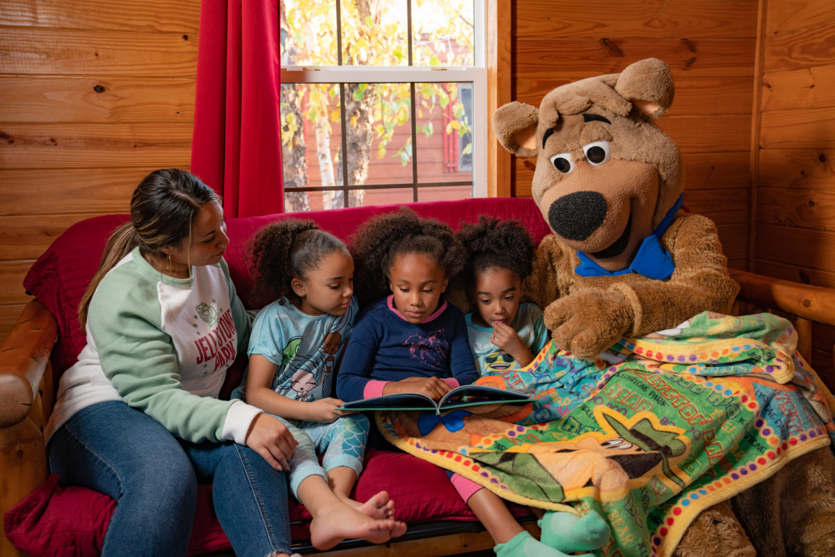 Boo Boo Bear reading a bedtime story to kids in a cabin at Jellystone Park South Haven